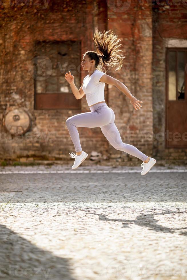 jonge vrouw juping hoog tijdens training in de stedelijke omgeving foto