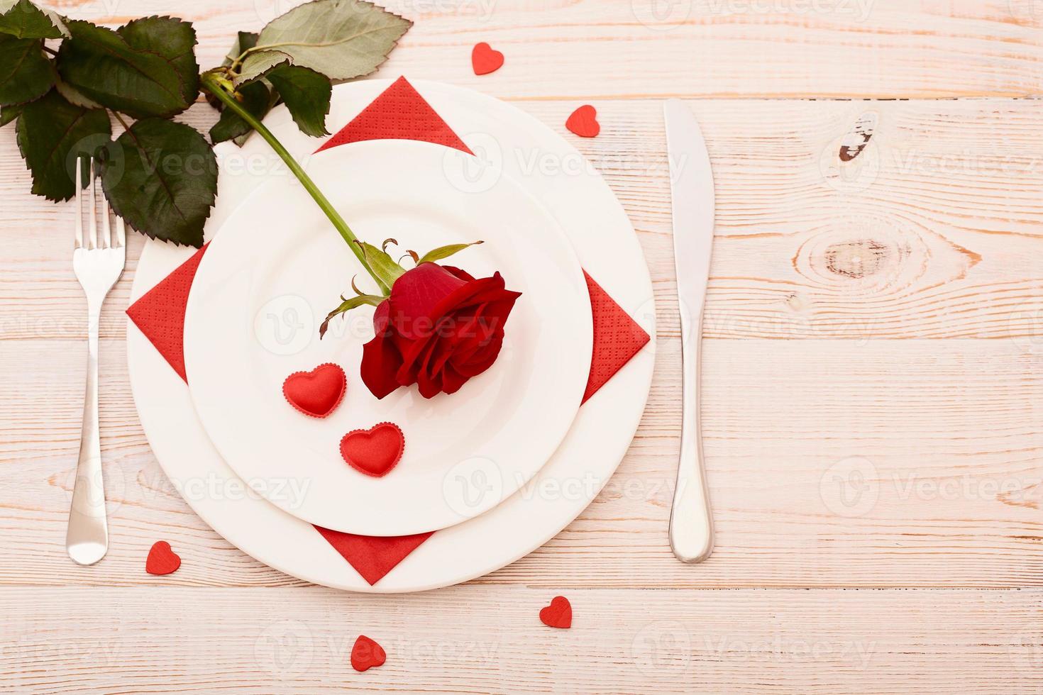 top visie van serviesgoed van ronde en hart vormig leeg bord, metaal mes en vork geserveerd Aan wit houten tafel met gloeiend kaars en geschenk doos bereid voor viering van heilige Valentijn dag foto
