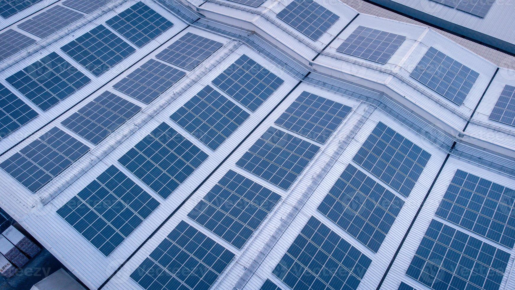 een groot zonne- cel dak Aan een industrieel gebouw genereren elektriciteit voor de fabriek gedurende dag volgens naar beleid en maatregelen naar verminderen globaal opwarming door nemen hoge Hoek schoten van drones foto