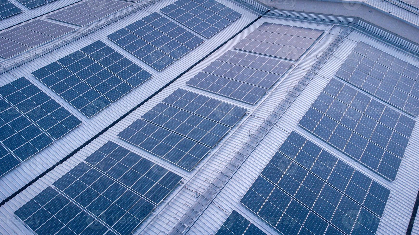 een groot zonne- cel dak Aan een industrieel gebouw genereren elektriciteit voor de fabriek gedurende dag volgens naar beleid en maatregelen naar verminderen globaal opwarming door nemen hoge Hoek schoten van drones foto