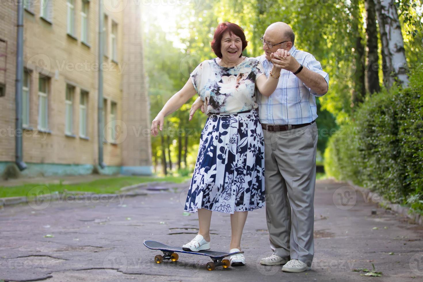 gelukkig ouderen paar met een skateboard. knap Mens en vrouw senior burgers. man en vrouw van oud leeftijd voor een wandelen in de stad. foto