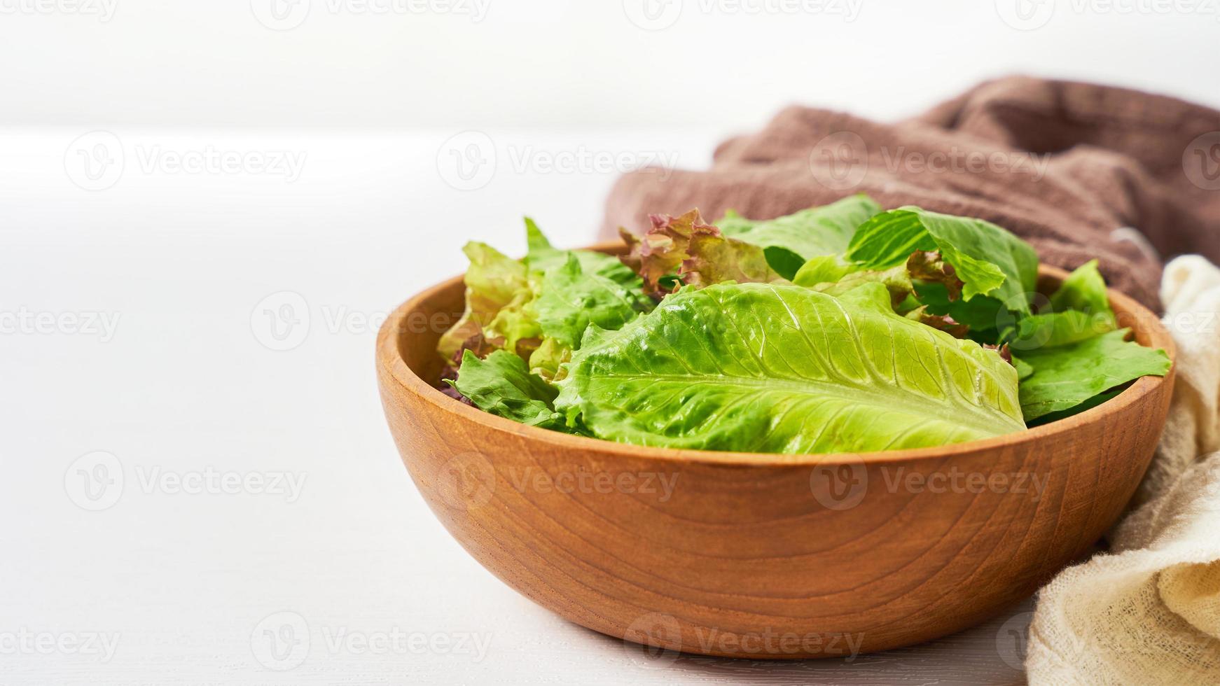 vers salade van groen bladeren in een houten kom Aan wit schoon humeur achtergrond met kopiëren ruimte. lepel en vork foto