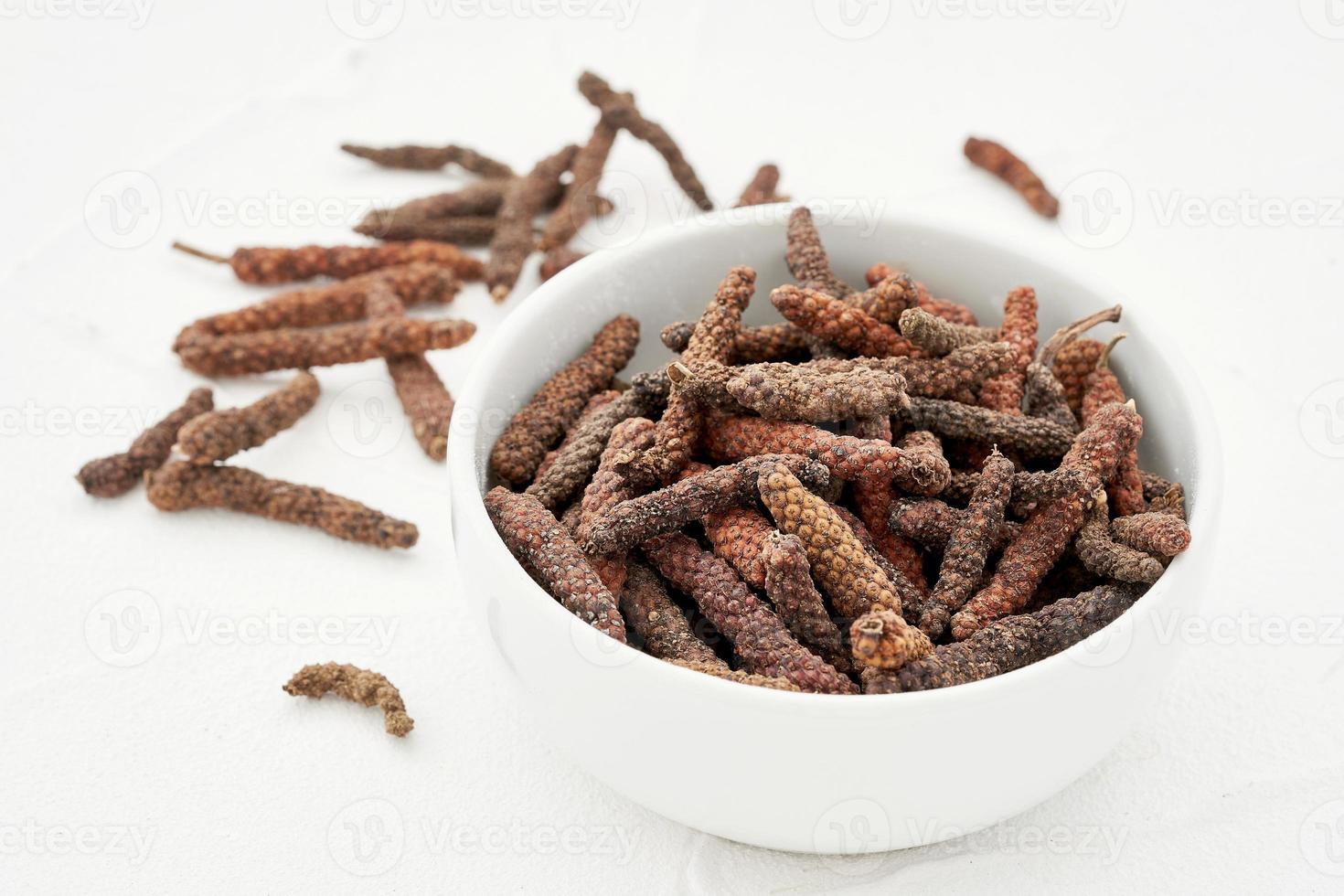 lang peper of pijper longum in bord Aan wit tafel achtergrond. hoop van lang peper of pijper longum. lang peper, pijper longum foto