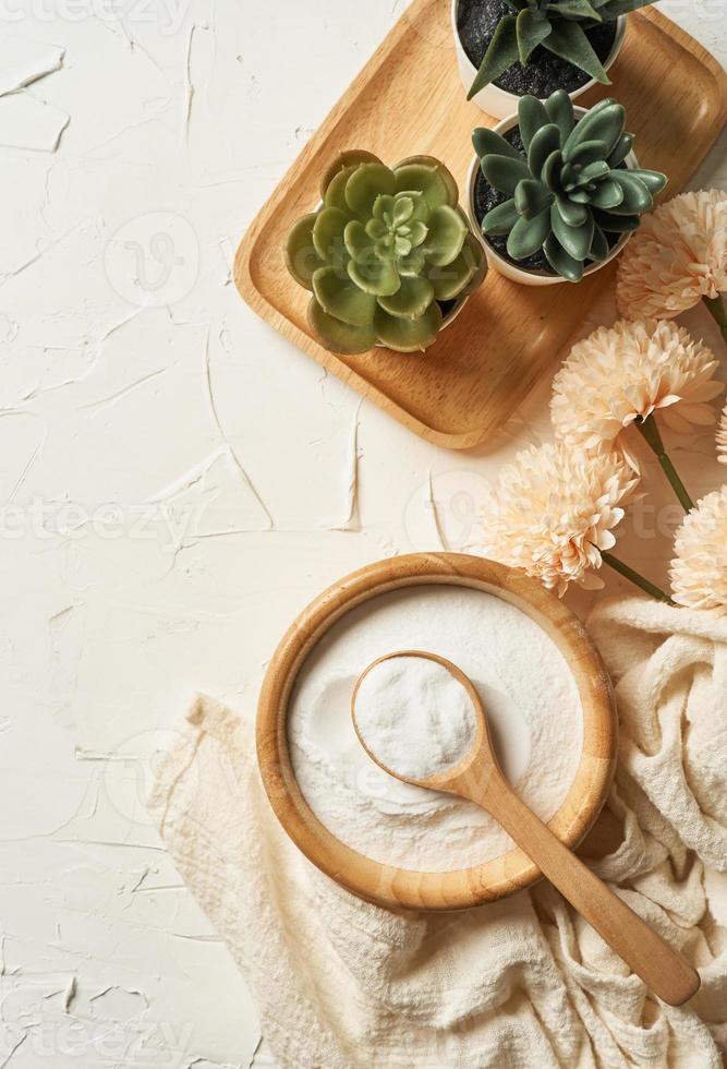 schoonheid concept van collageen poeder in een houten kom en lepel Aan wit tafel achtergrond. Gezondheid supplement, eiwit inname. bloem en groen fabriek. top visie of vlak leggen foto