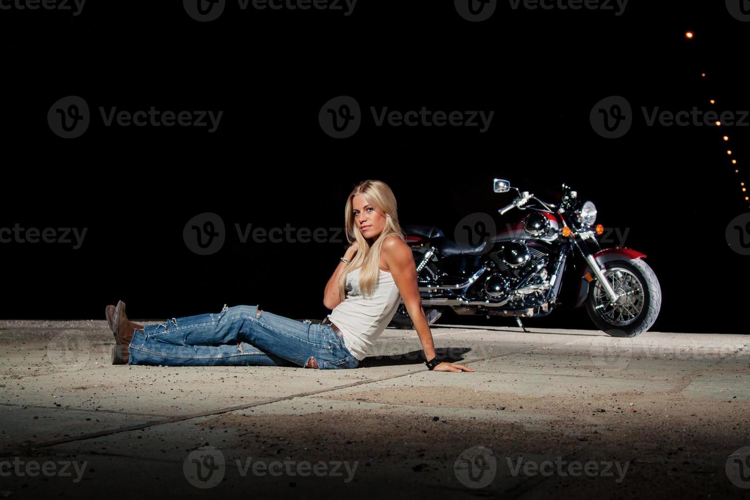 sexy blonde zit in de buurt van haar motorfiets foto