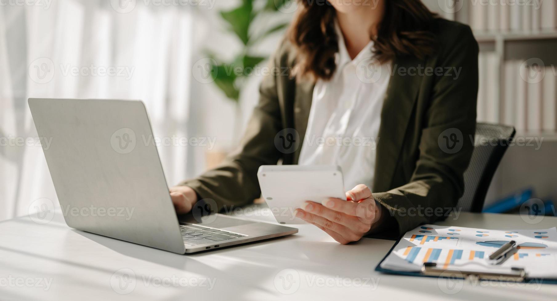 vrouwen tellen munten op rekenmachine uit het spaarvarken. hand met pen bezig met rekenmachine om op bureau te berekenen over de kosten op kantoor aan huis. foto