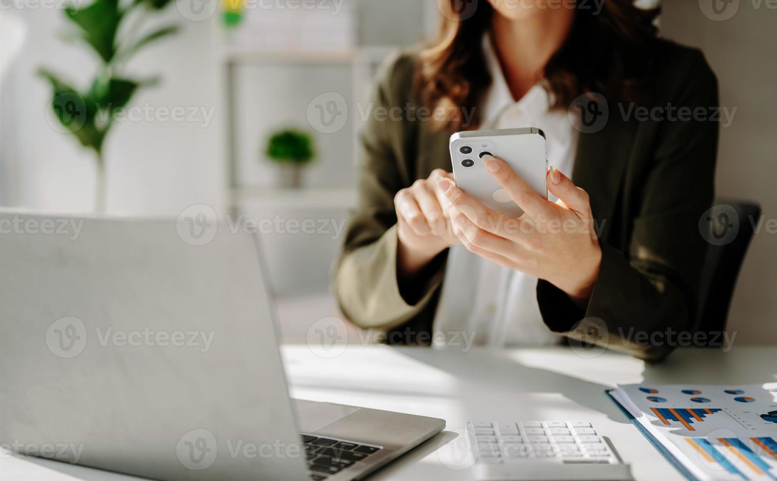 zelfverzekerd zakenvrouw werken Aan notebook, tablet en tablet Bij haar werkplaats Bij kantoor. foto
