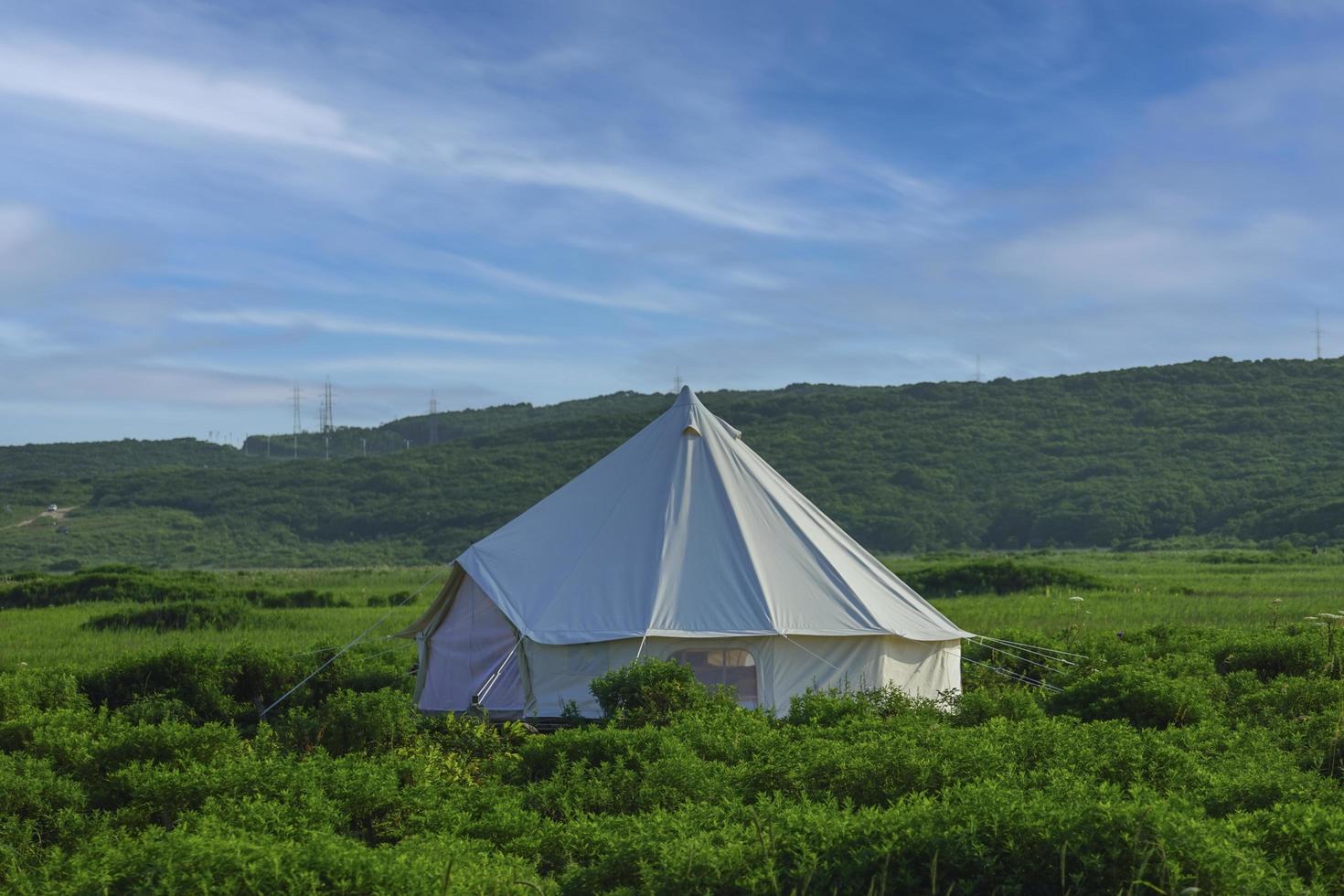 witte tent in een veld met bewolkte blauwe hemel foto
