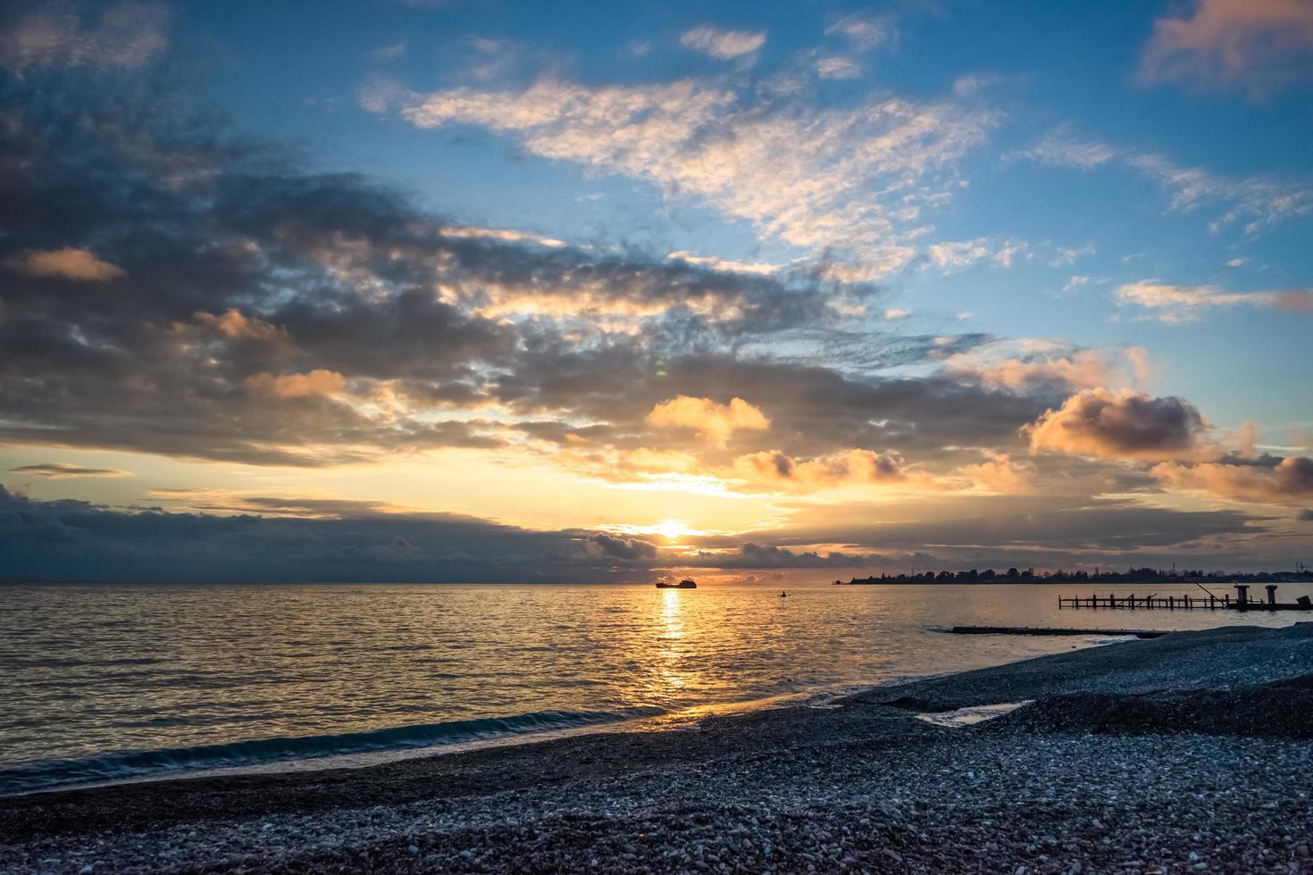 kleurrijke zonsondergang over een watermassa en een rotsachtige kust foto