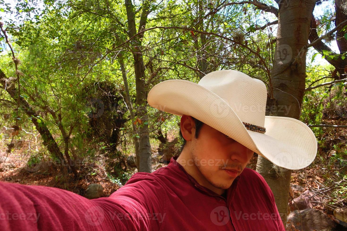 Mens in een rood overhemd en een wit cowboy hoed is nemen een selfie. foto