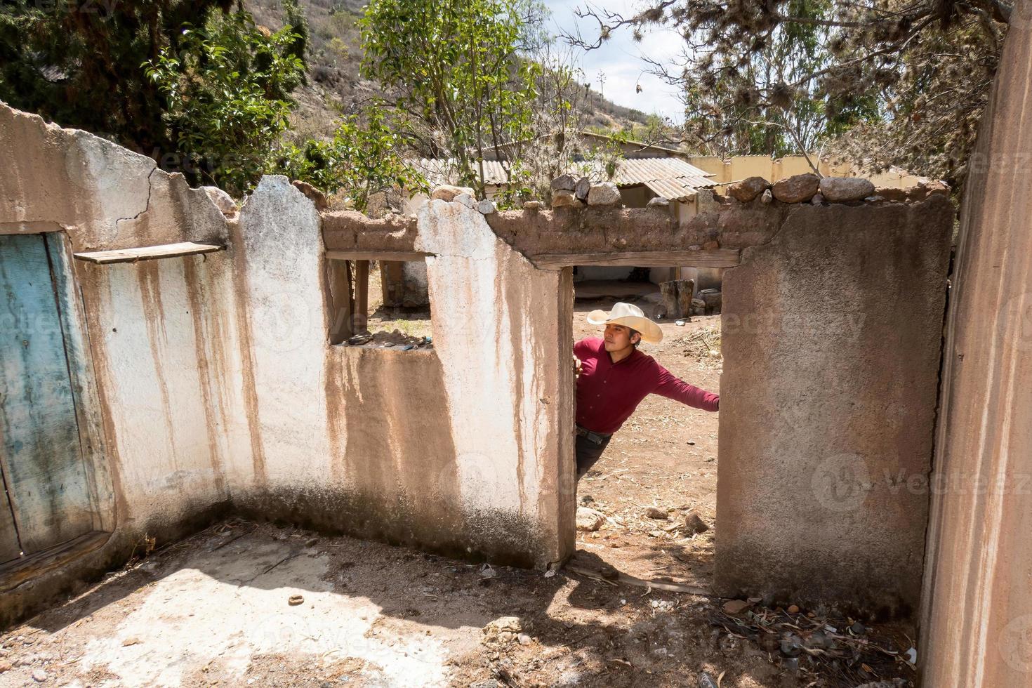 Mens met een cowboy hoed op zoek Bij de verlaten huis van zijn grootouders in Mexico foto