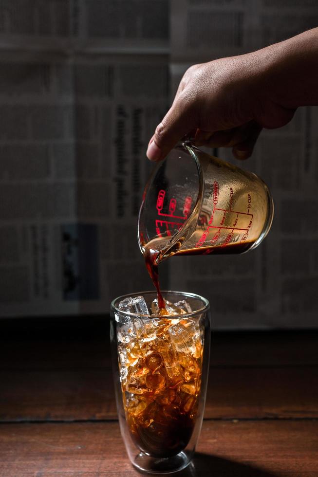 barista melk gieten in een glas ijskoffie foto