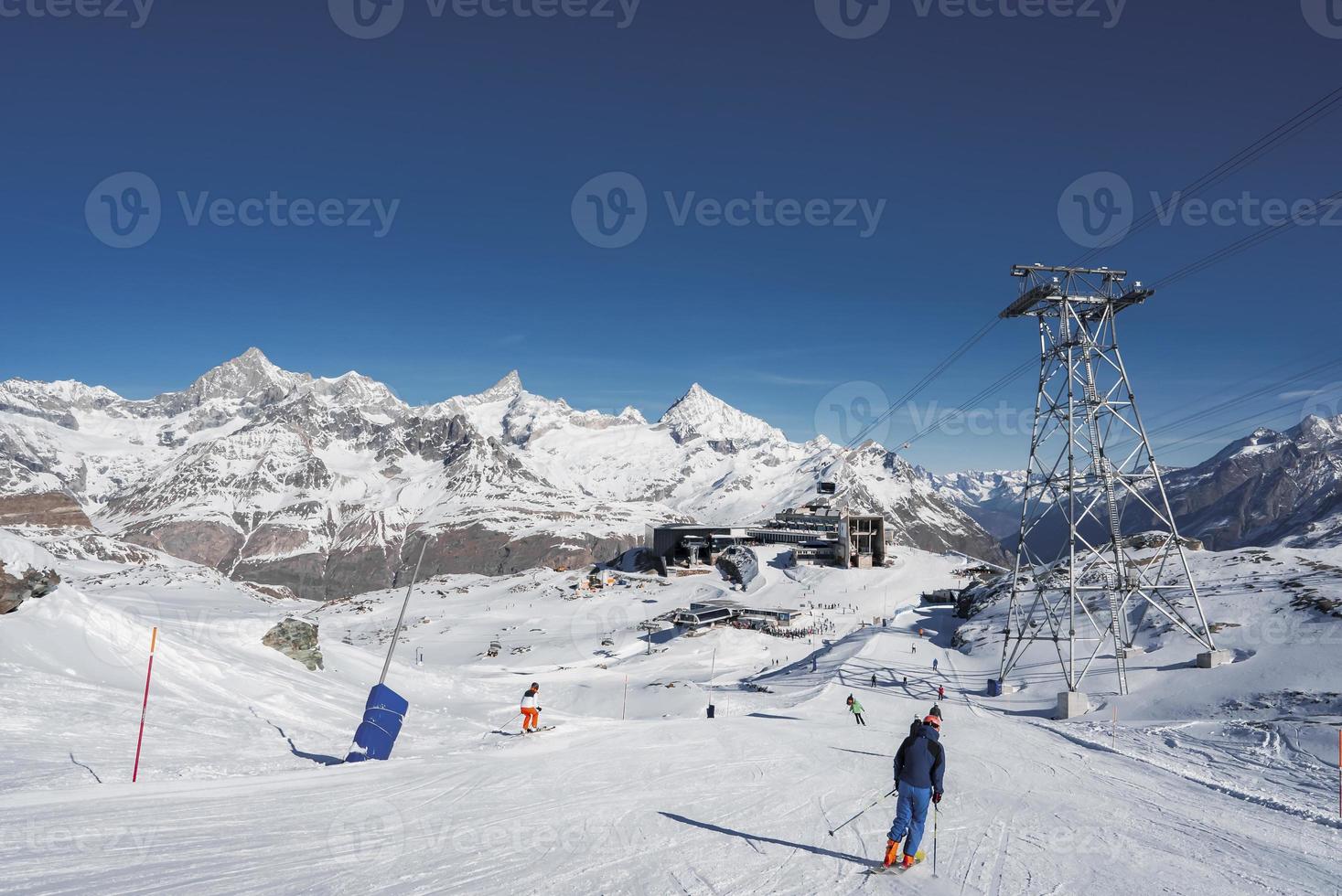 achterzijde visie van skiër met polen skiën Aan besneeuwd landschap foto