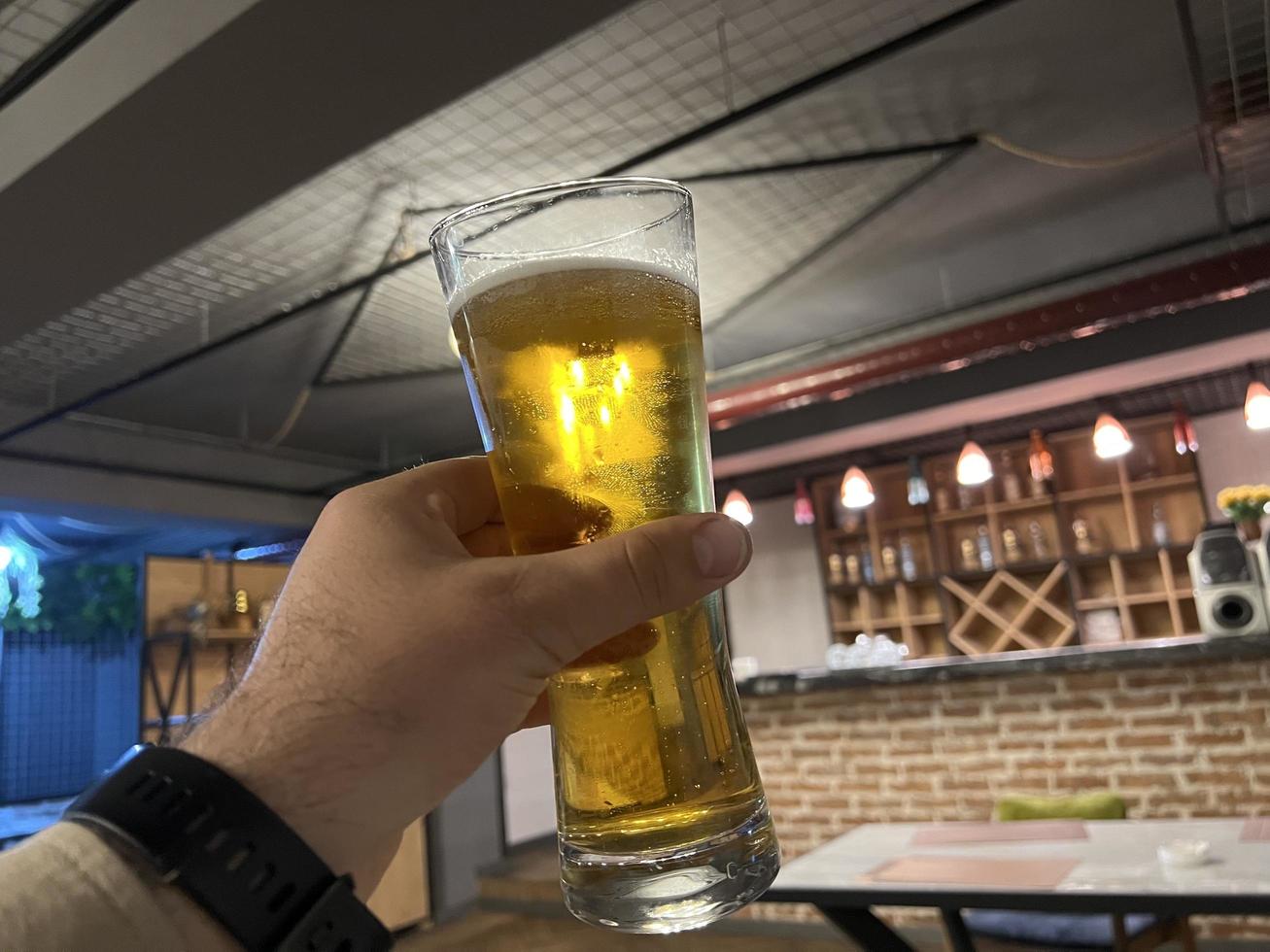 man's hand- Holding een bier glas in een kroeg of restaurant. foto