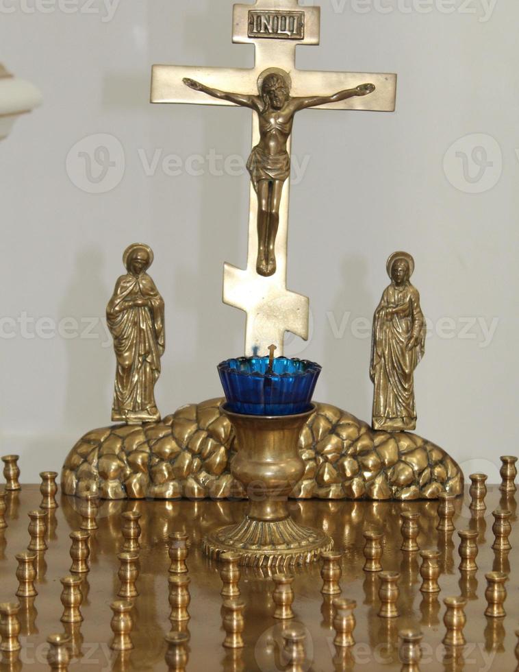christenen licht kaarsen in voorkant van de orthodox kruis met de kruisbeeld, de concept van orthodox geloof en geloof. foto