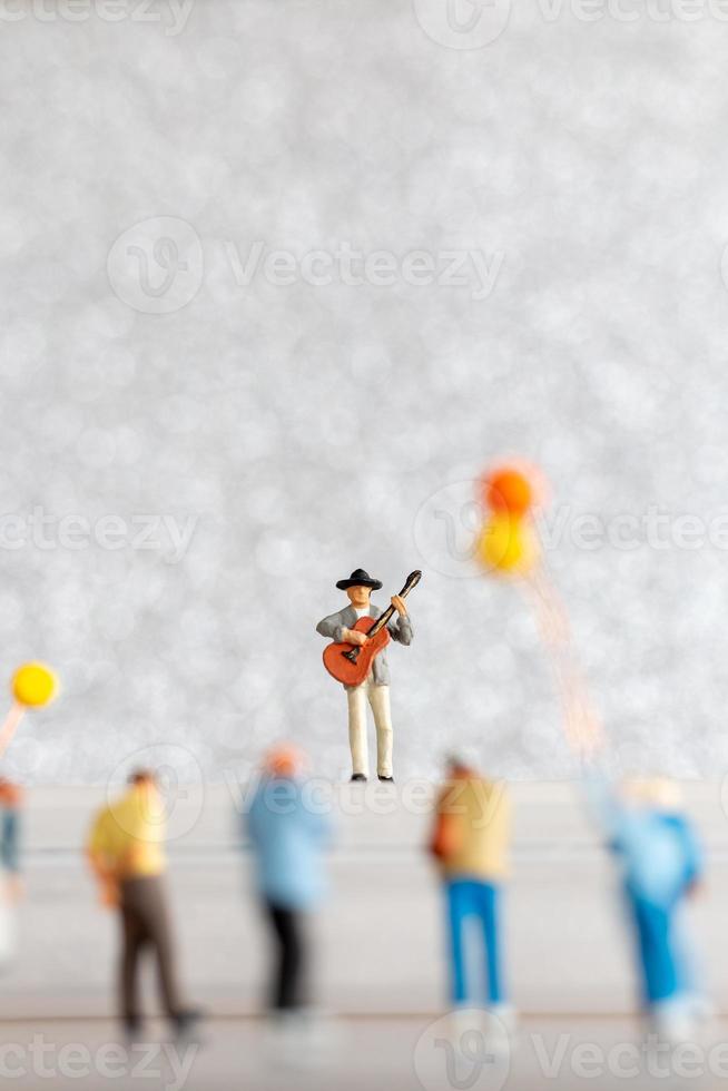 miniatuur musicus spelen een gitaar Aan fase, wereld muziek- dag concept foto