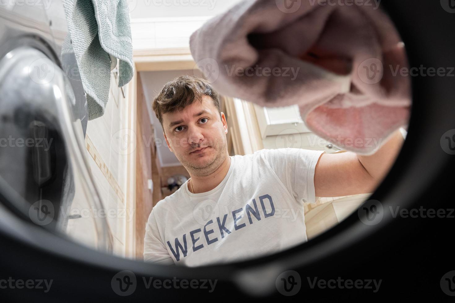 Mens visie van het wassen machine binnen. mannetje doet wasserij dagelijks routine. foto