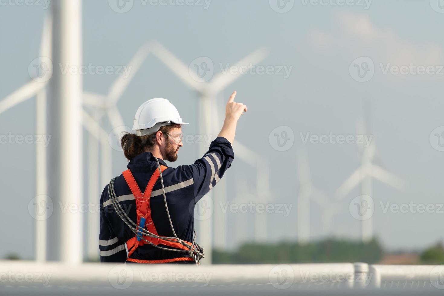 ingenieur Bij natuurlijk energie wind turbine plaats met een missie naar beklimmen omhoog naar de wind turbine messen naar inspecteren de operatie van groot wind turbines dat bekeerlingen wind energie in elektrisch energie foto