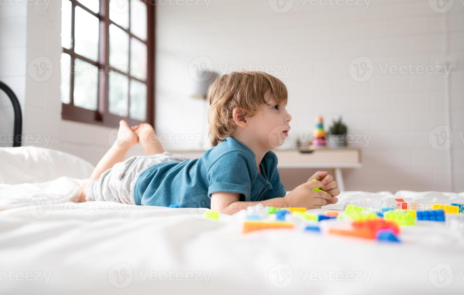 weinig jongen in zijn slaapkamer met een nieuw speelgoed- gekocht door zijn ouders naar helpen hem verbeteren zijn denken vaardigheden. foto