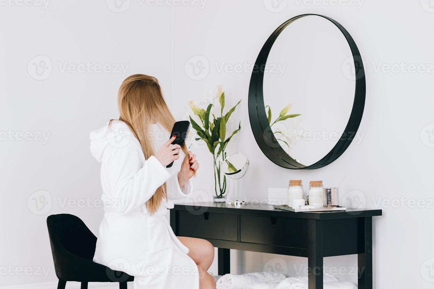 meisje kijkt naar haar spiegelbeeld met een haarborstel foto