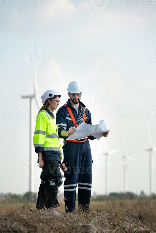 Mens en vrouw ingenieur gestationeerd Bij de natuurlijk energie wind turbine plaats. met dagelijks audit taken van majoor wind turbine operaties dat transformeren wind energie in elektrisch elektriciteit foto