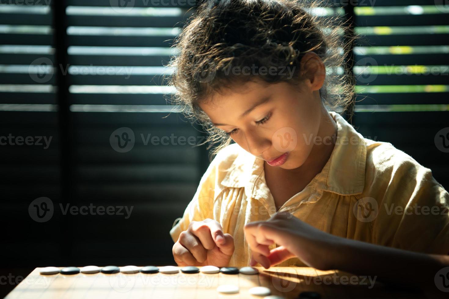 portret van een weinig meisje in kantoor kamer van huis met een spel van Gaan wezen geleerd naar bouwen concentratie en intelligentie. foto