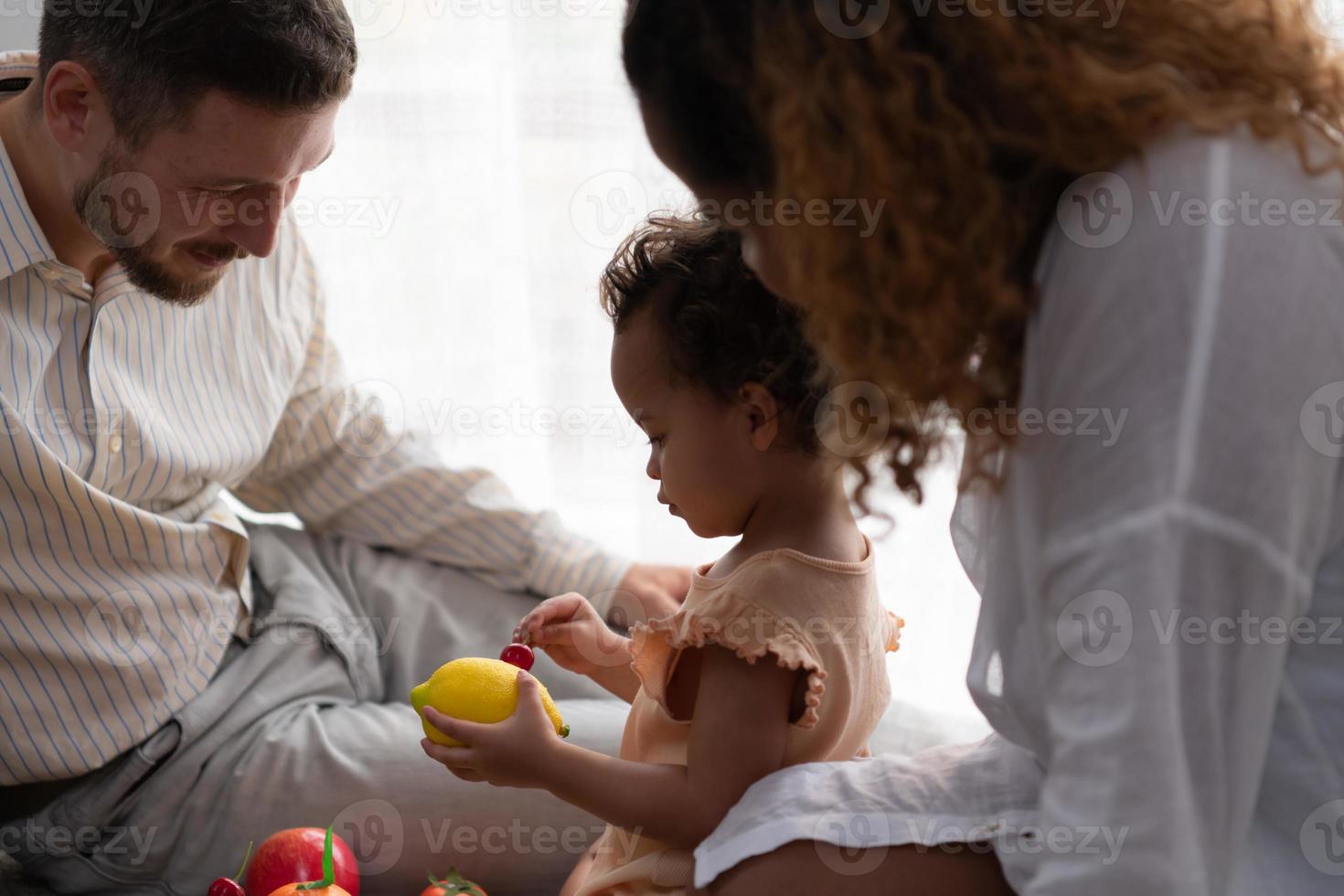 ouders en kinderen kom tot rust in de leven kamer van de huis. kijk maar baby gelukkig Speel met zijn favoriete speelgoed. foto