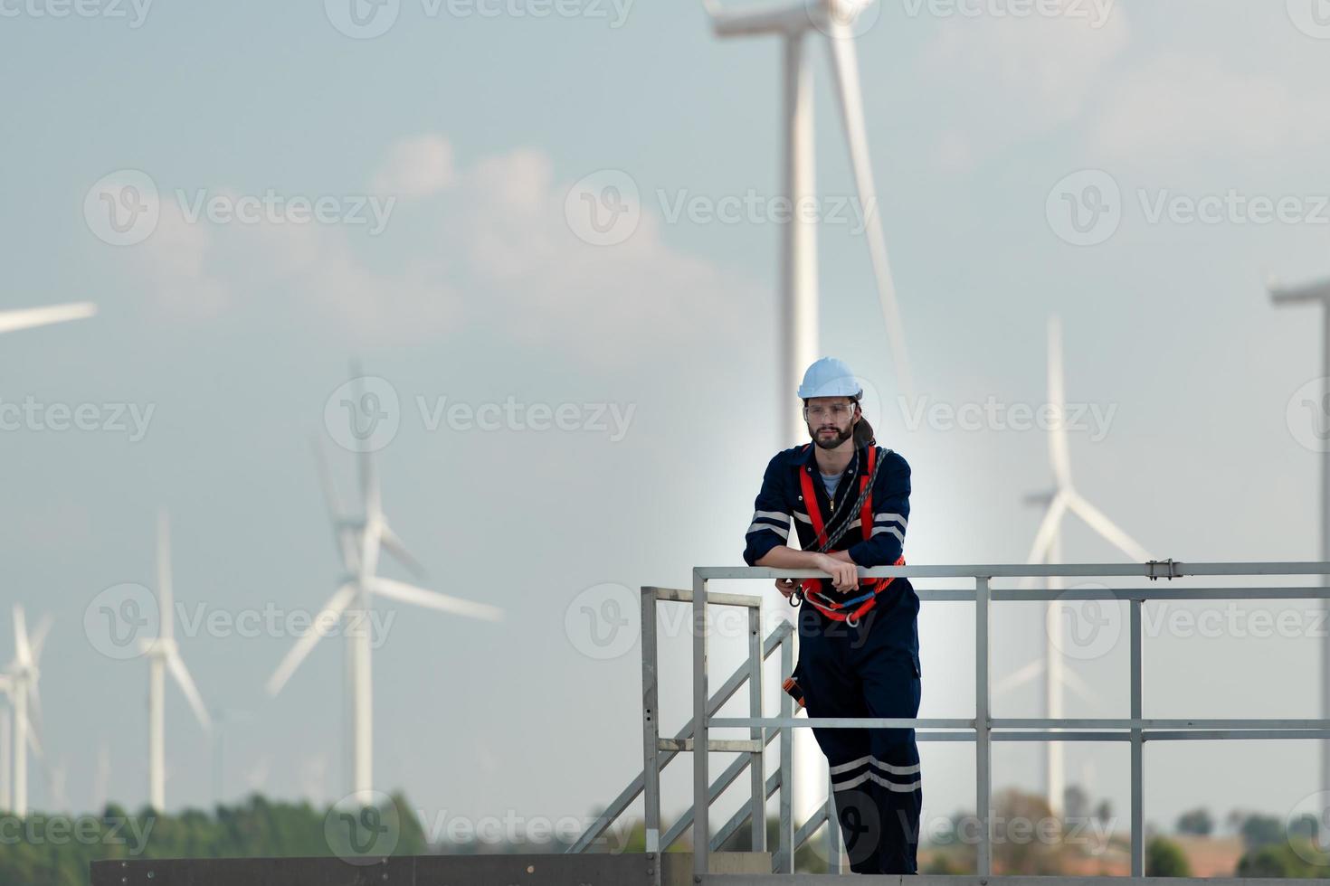 ingenieur Bij natuurlijk energie wind turbine plaats met een missie naar beklimmen omhoog naar de wind turbine messen naar inspecteren de operatie van groot wind turbines dat bekeerlingen wind energie in elektrisch energie foto
