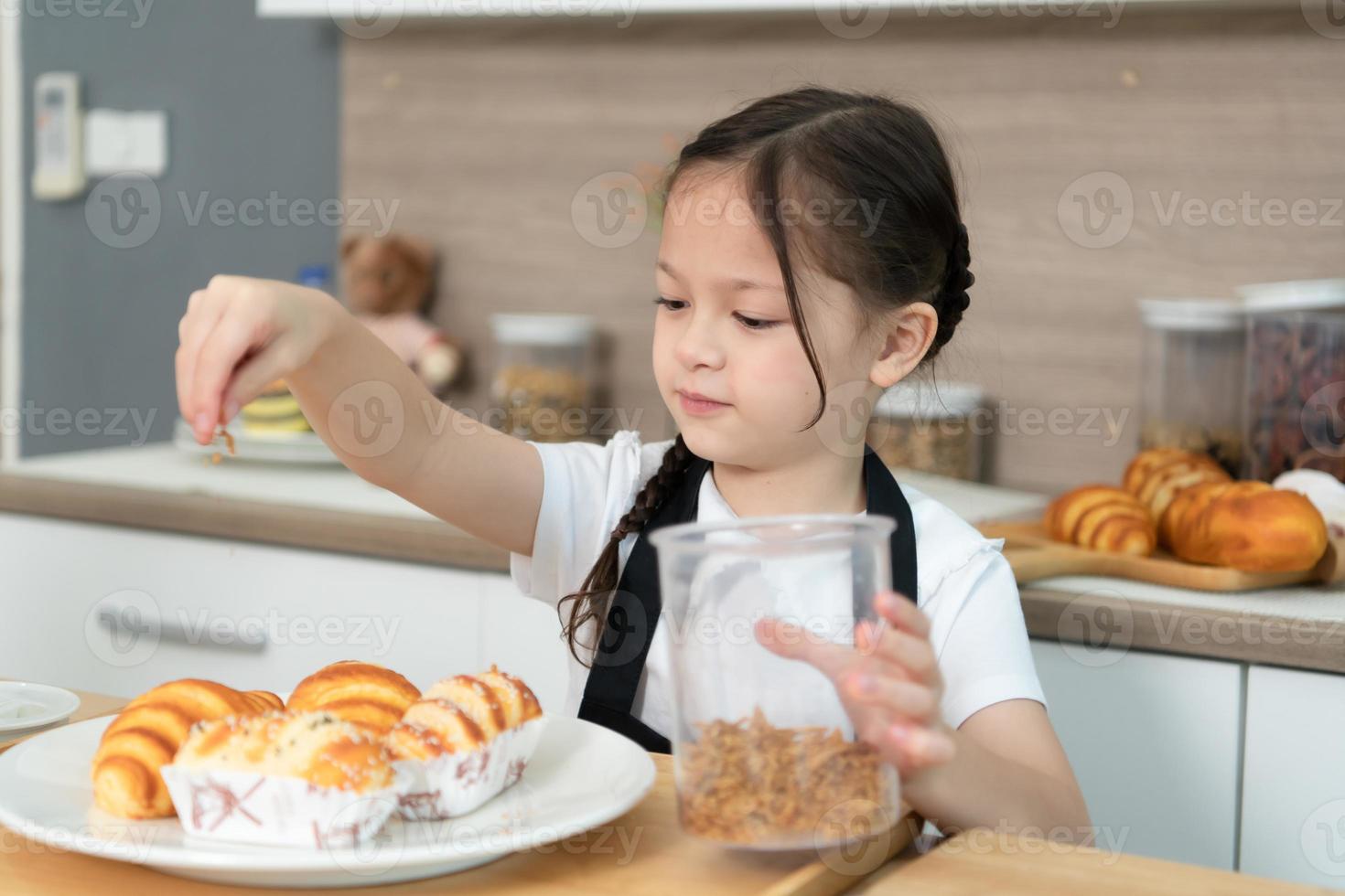 portret van een weinig meisje in de keuken van een huis hebben pret spelen bakken brood foto