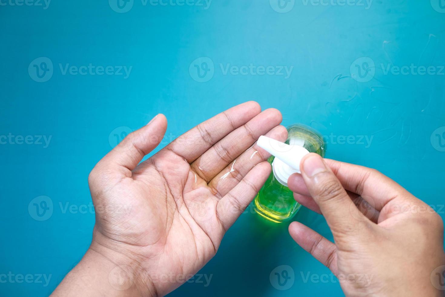 persoon handdesinfecterend middel op een blauwe achtergrond toe te passen foto