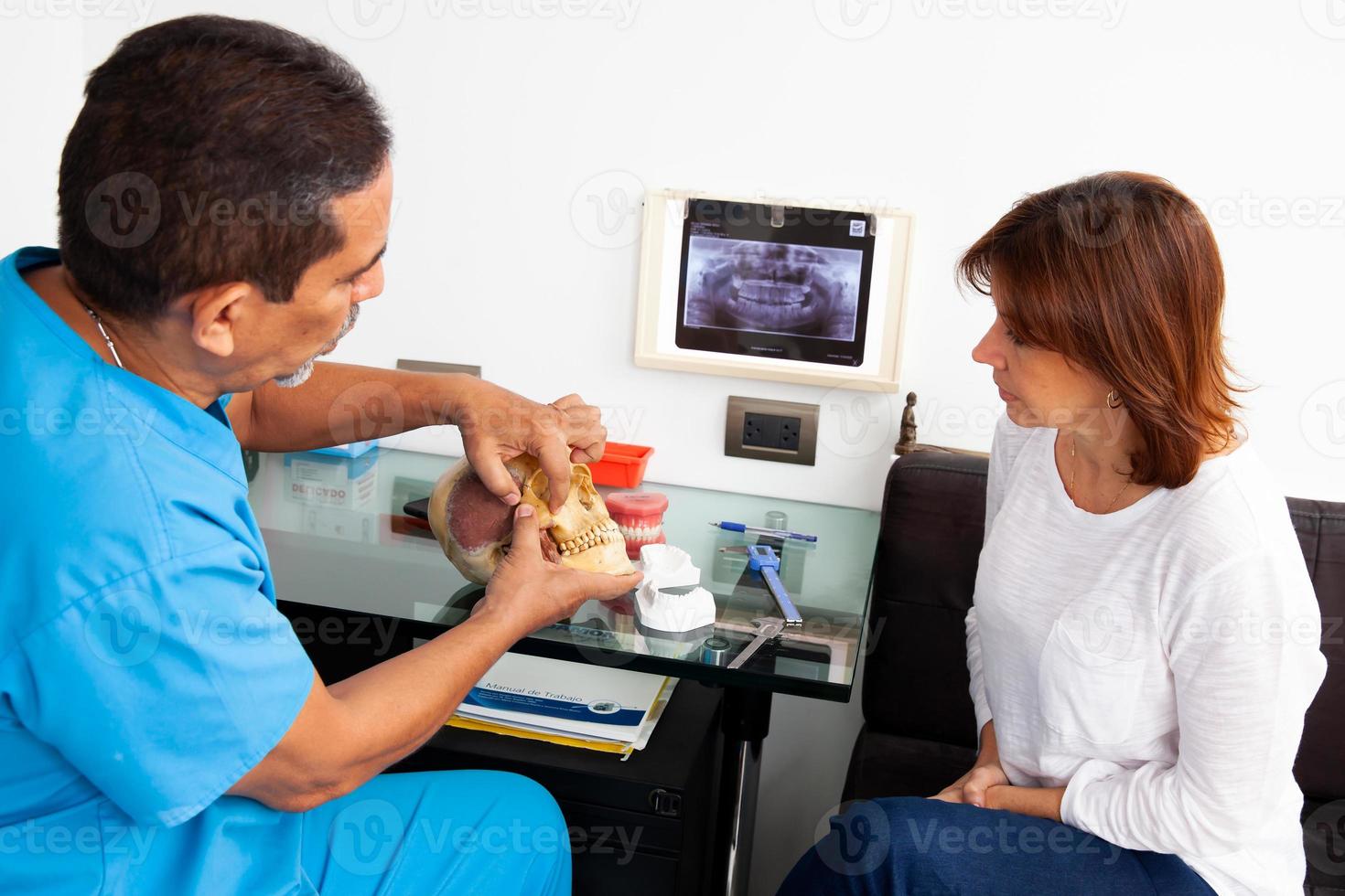 tandarts gebruik makend van een menselijk schedel net zo model- naar leg uit haar tandheelkundig behandeling naar een vrouw geduldig foto