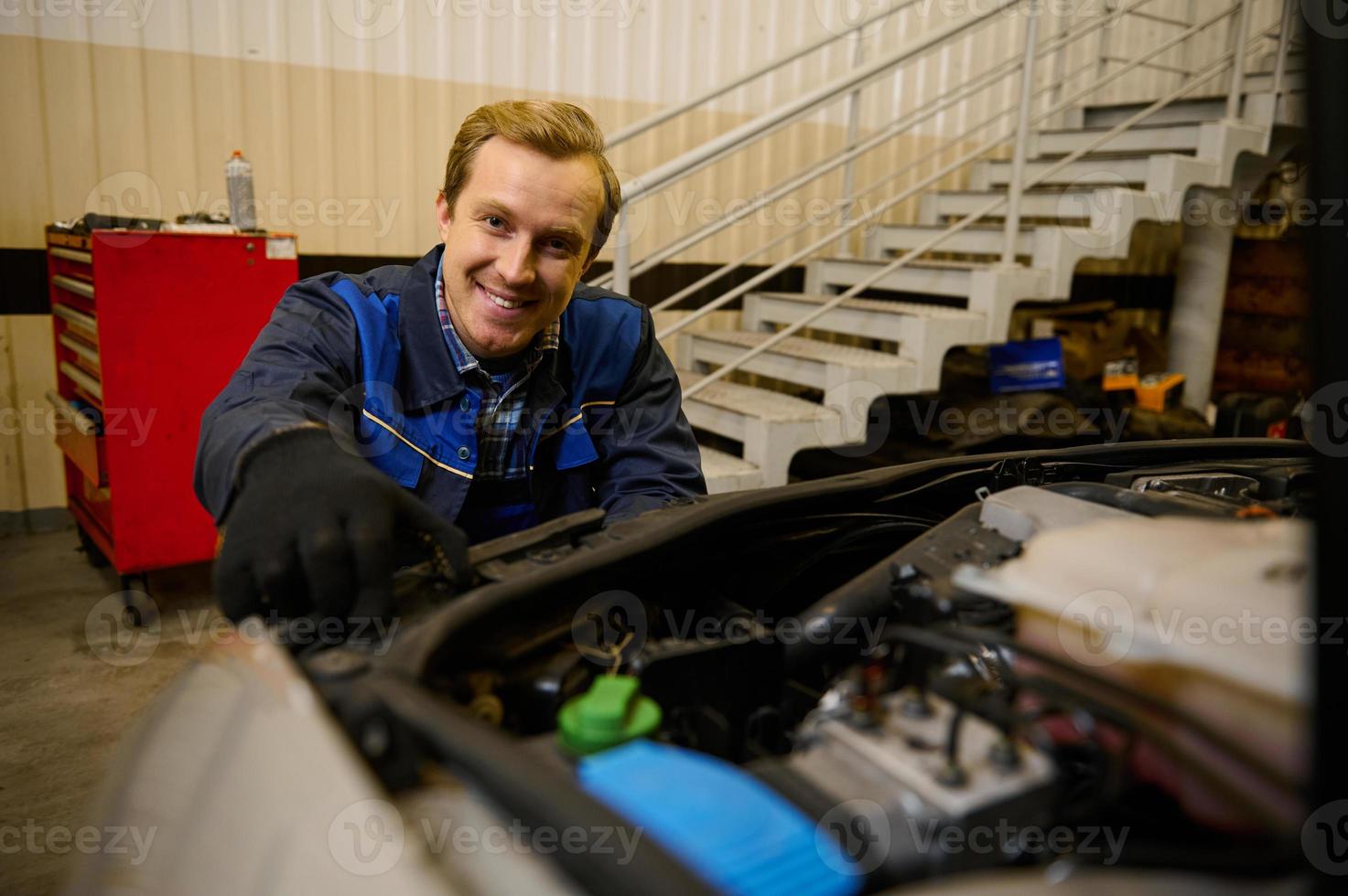 knap jong Kaukasisch auto ingenieur, technicus monteur in auto onderhoud aanpassen koplampen Aan auto in de reparatie winkel garage. auto onderhoud, auto reparatie en garantie onderhoud concept foto
