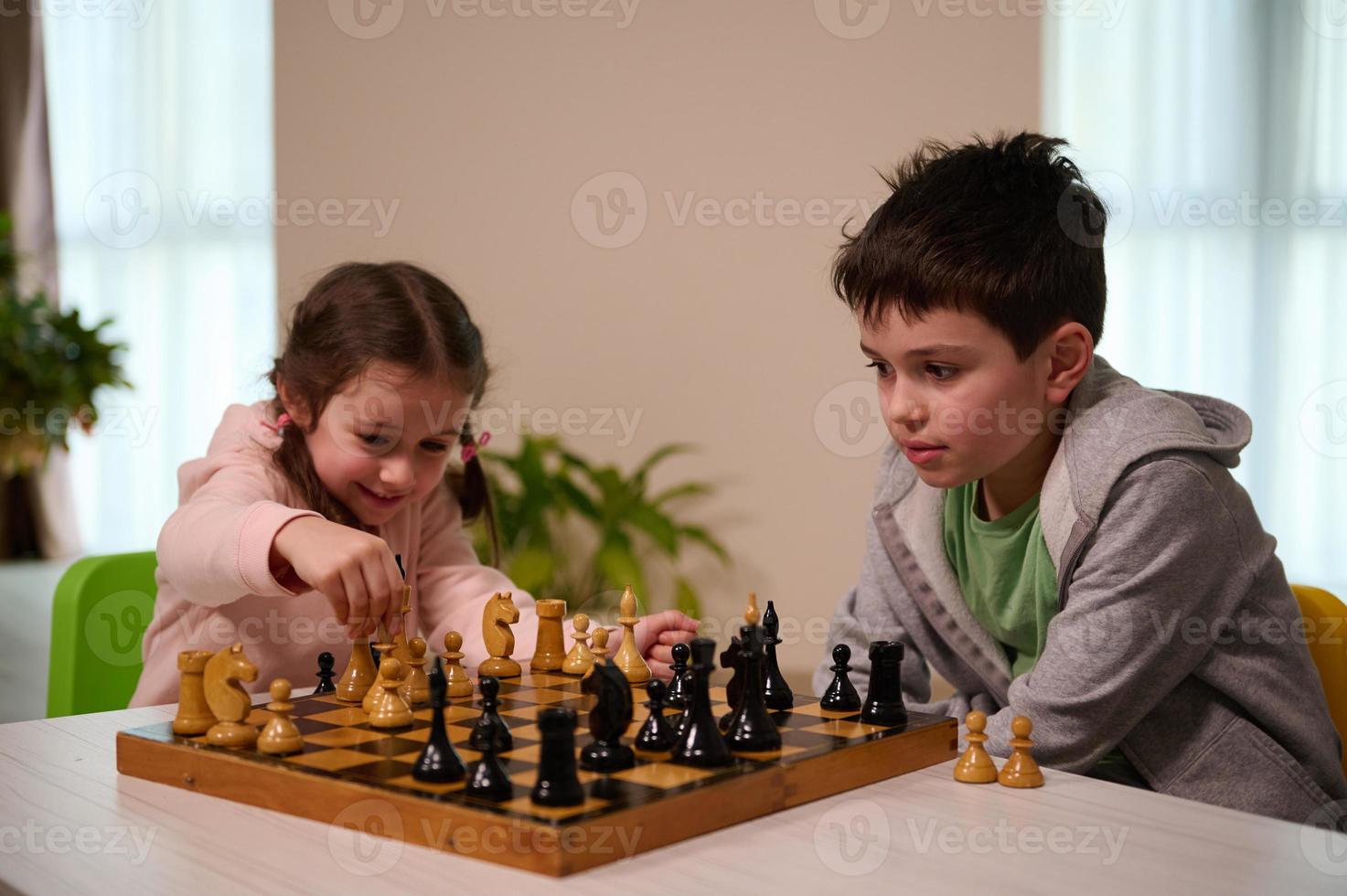 kinderen hebben Super goed tijd samen spelen schaken. broer onderwijs zijn jonger zus spelen schaak spel. logica ontwikkeling, vrije tijd bord spellen, amusement, intelligent hobby en onderwijs concept foto