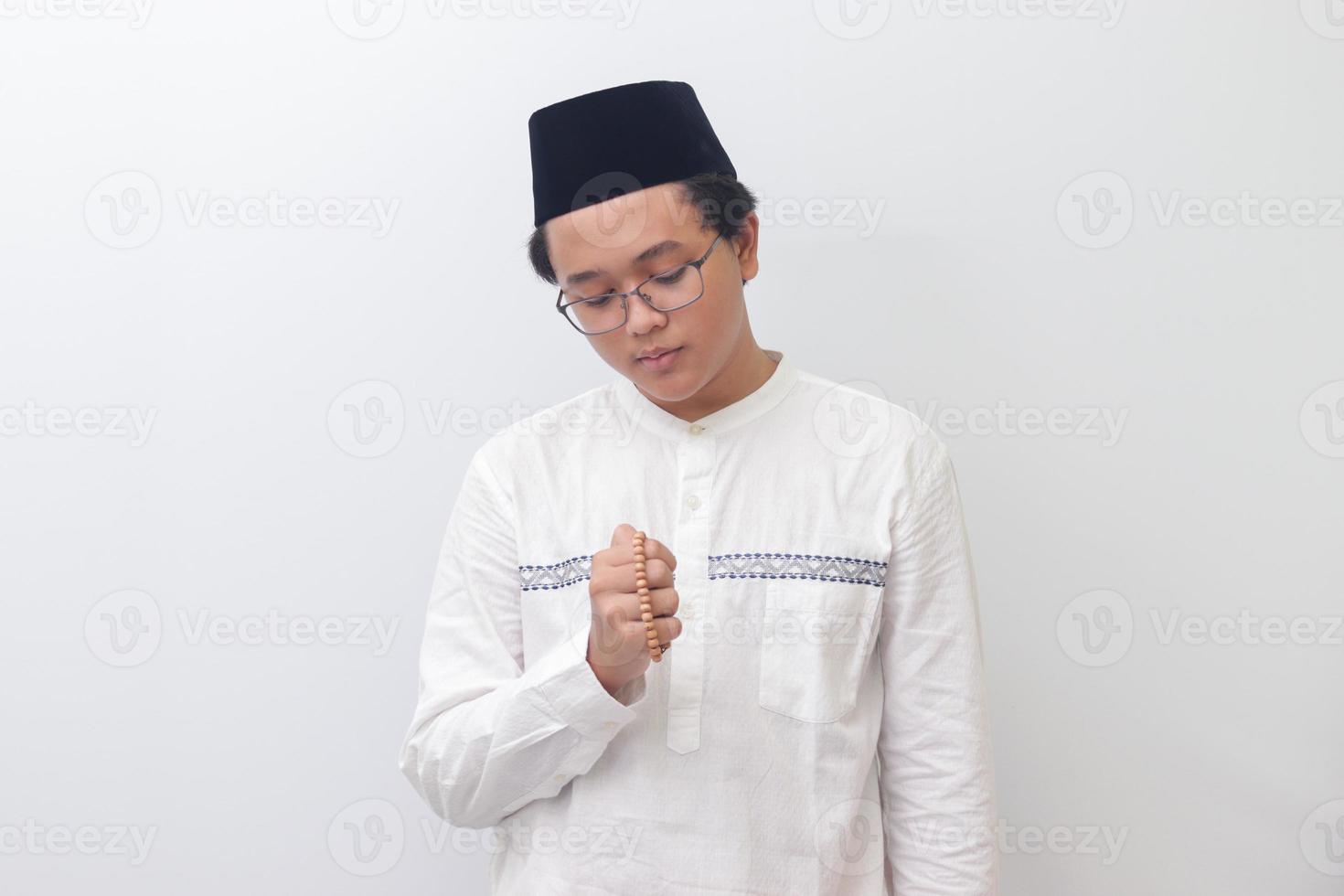 portret van jong attent Aziatisch moslim Mens bidden met Islamitisch kralen. geïsoleerd beeld Aan wit achtergrond foto