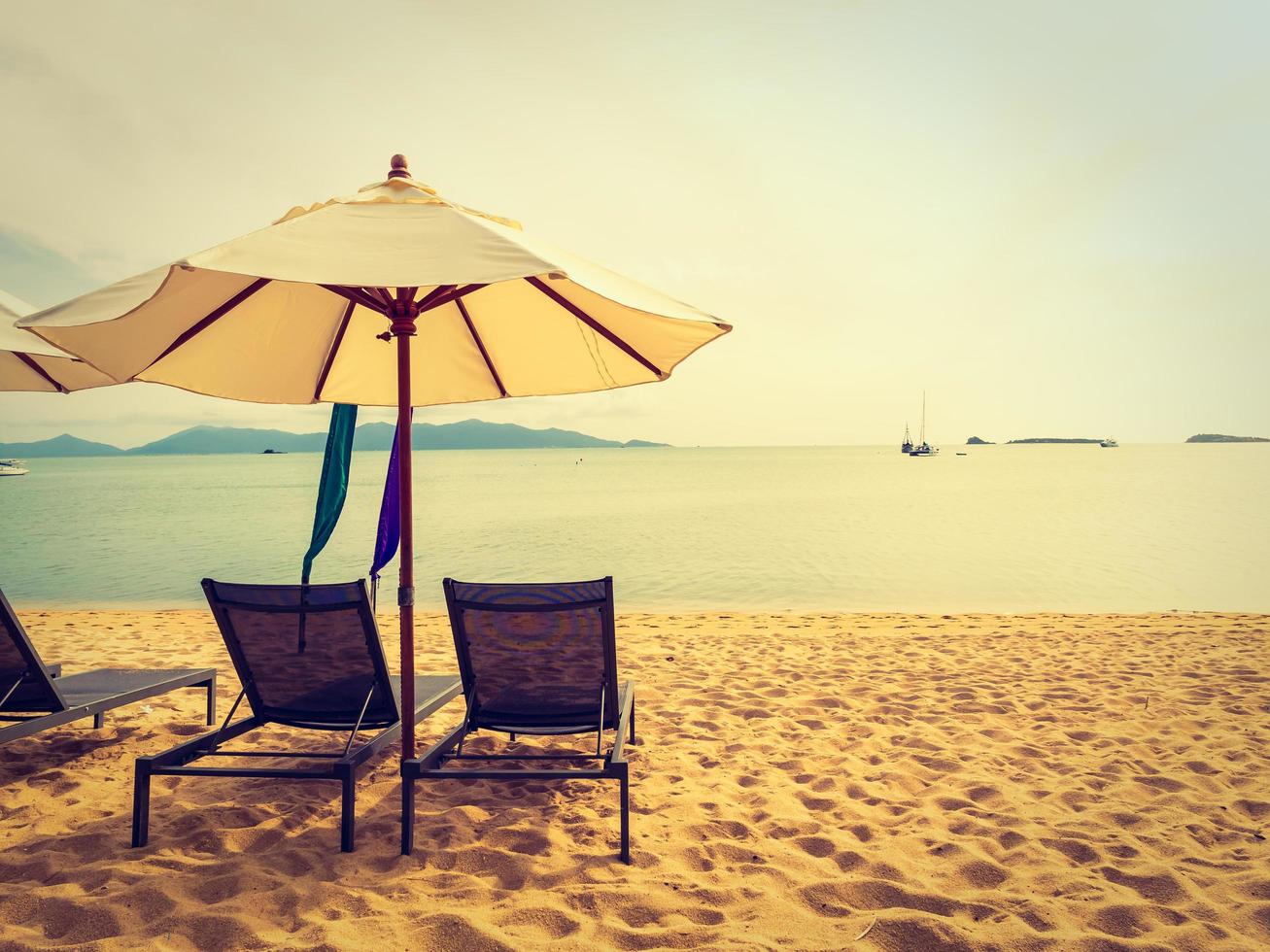 paraplu en stoel op het tropische strand, zee en oceaan bij zonsopgang foto