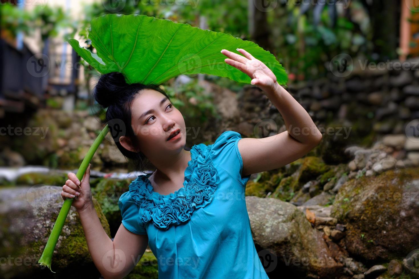 vrouw blokkeert regen met een gigantisch blad foto