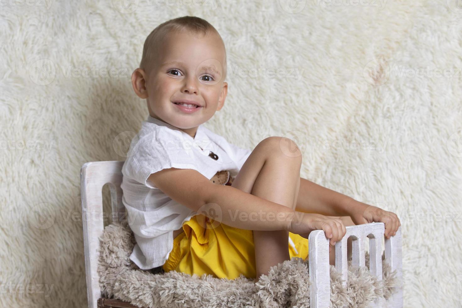 schattig weinig baby Aan een speelgoed- bed. drie jaar oud vrolijk jongen met een glimlach. foto