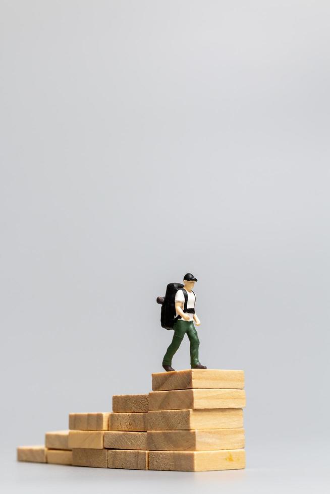 miniatuurmensen, reiziger die zich op houten blokken op een grijze achtergrond bevindt. reis- en avontuurconcept foto