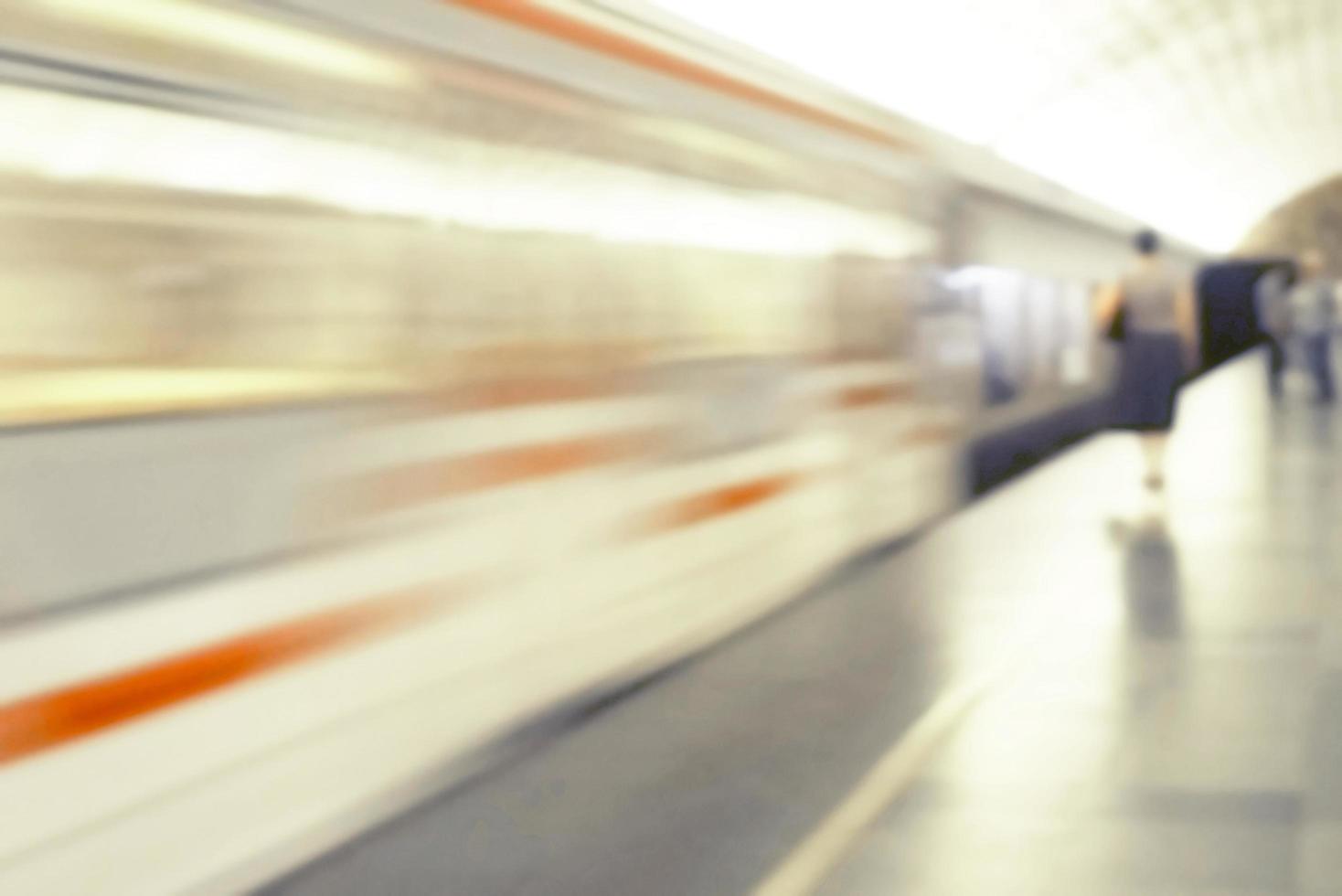 wazig beeld van een rijdende trein en menselijke silhouetten op het perron. foto