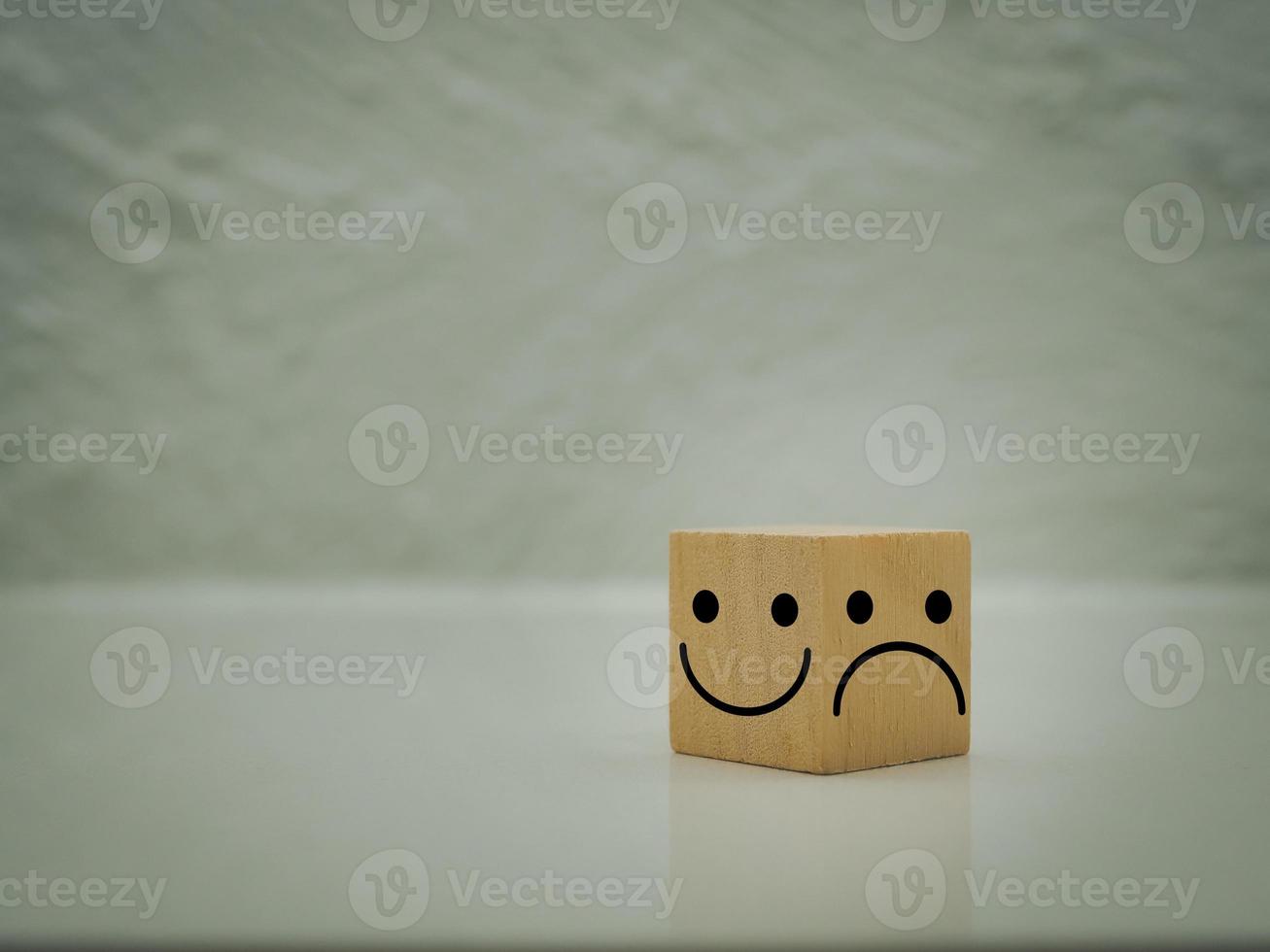 een houten kubus met een smiley of gelukkig gezicht. en frons of ontevredenheid elk kant kiest de uitdrukking van de gezicht. foto