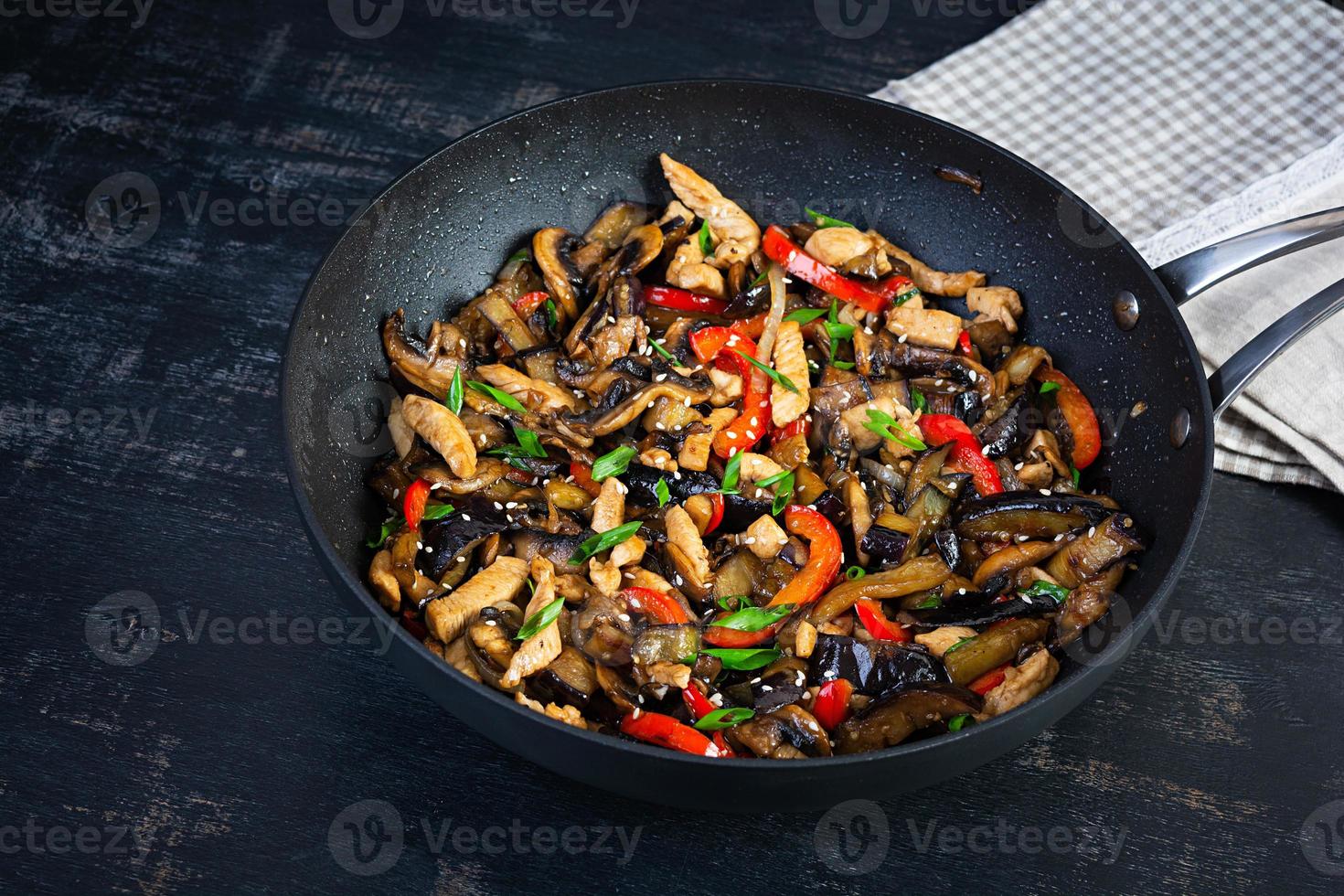 roeren bakken met kip, aubergine en peper in wok pan Aan donker achtergrond foto