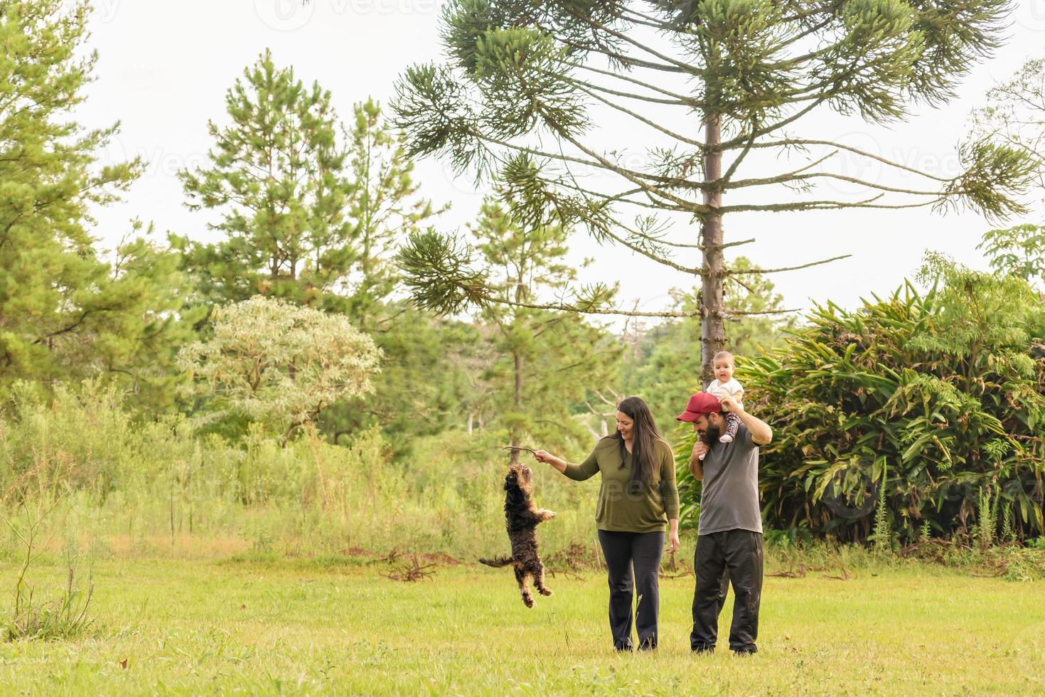 gelukkig familie, vader, moeder, baby meisje en puppy spelen in de park. foto