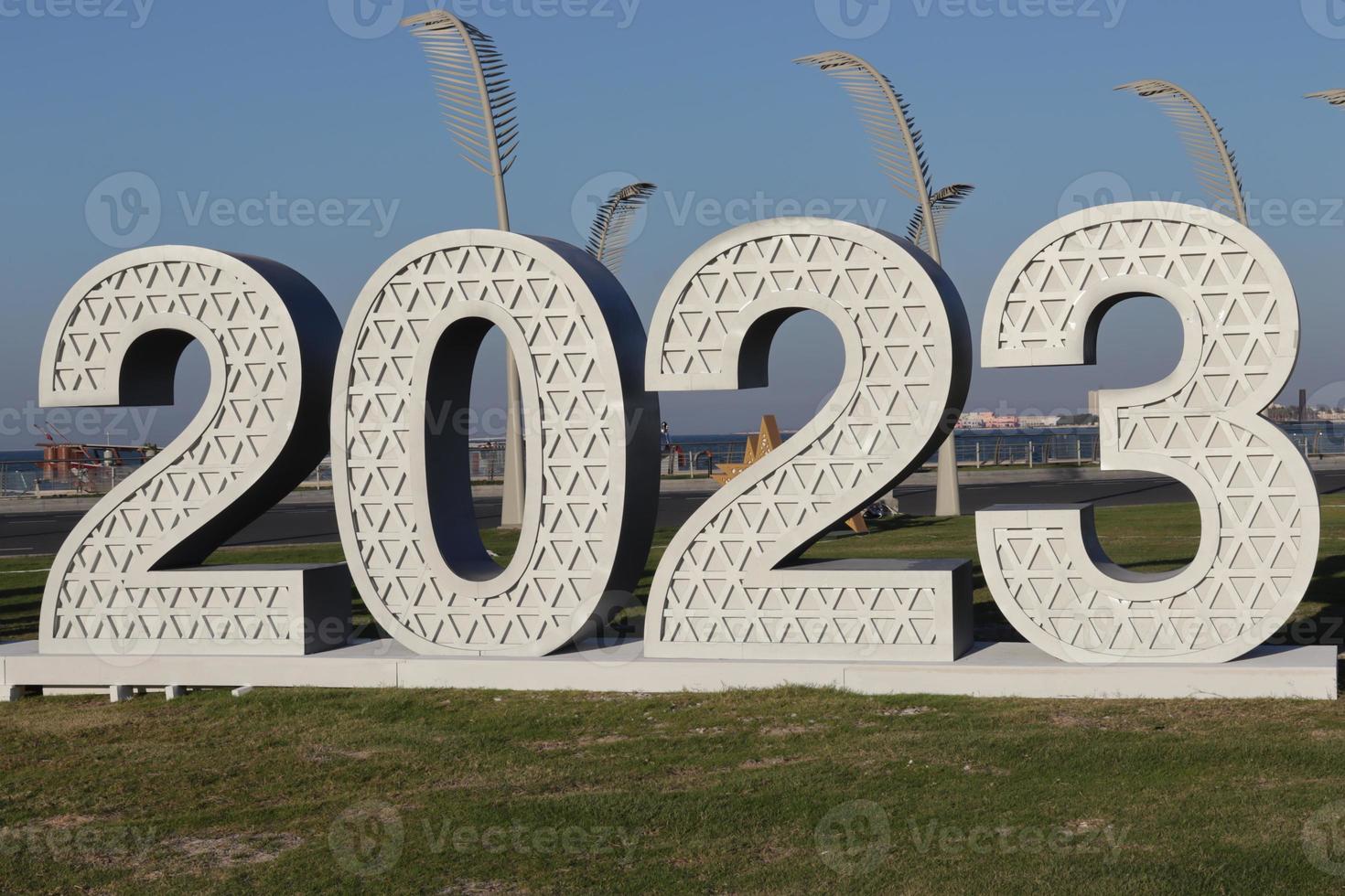 houten getallen van jaar 2023 Aan groen en blauw achtergrond , langs de weg foto