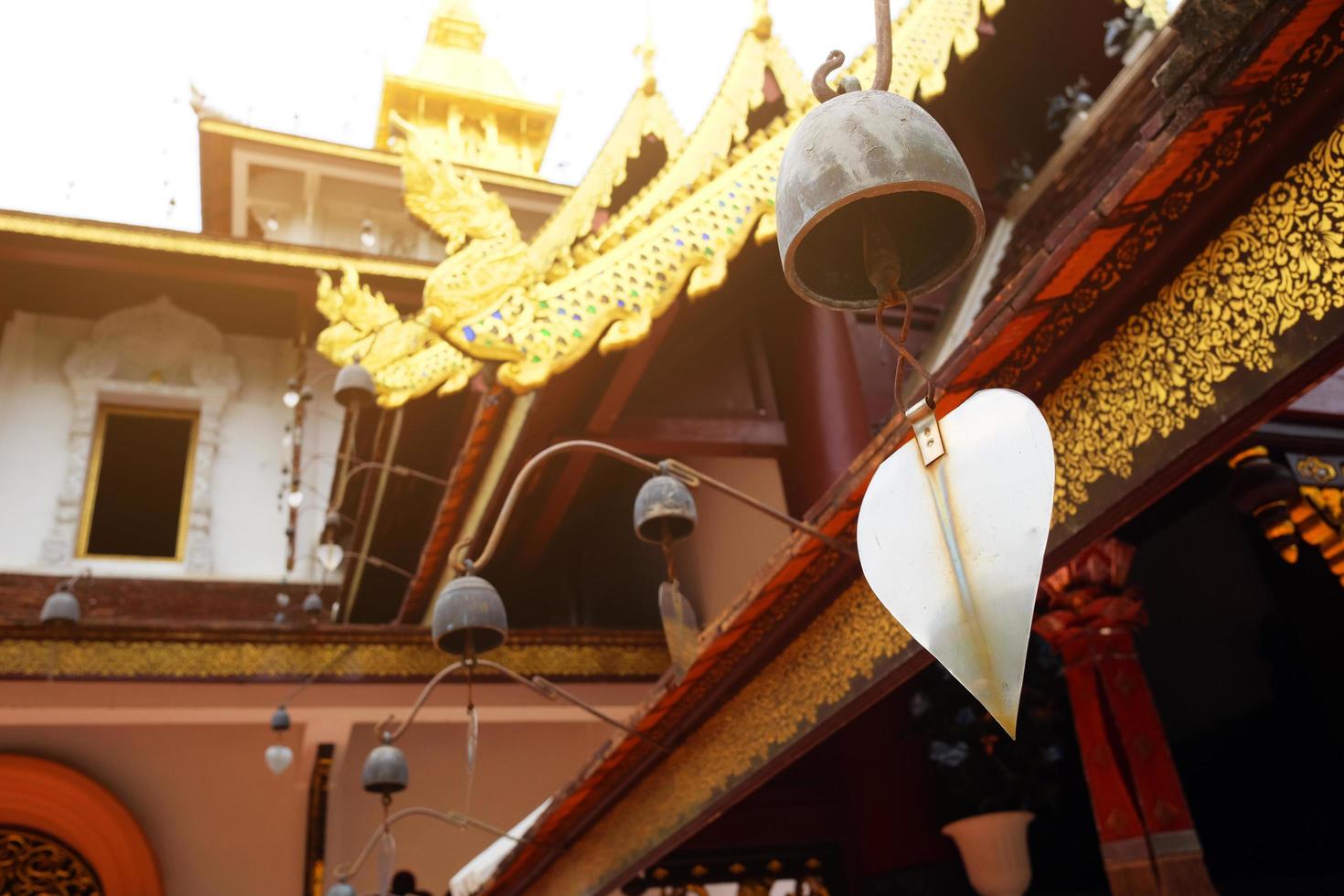 gouden naga en klokken hangende Aan kunst dak van boeddhistisch tempel met blauw lucht in Thailand foto