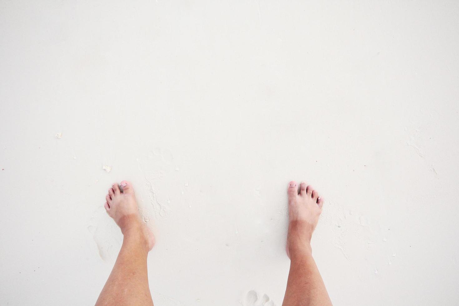 Aziatisch vrouw hebben tweekleurig voet huid met zonnebad Aan wit strand en zee foto