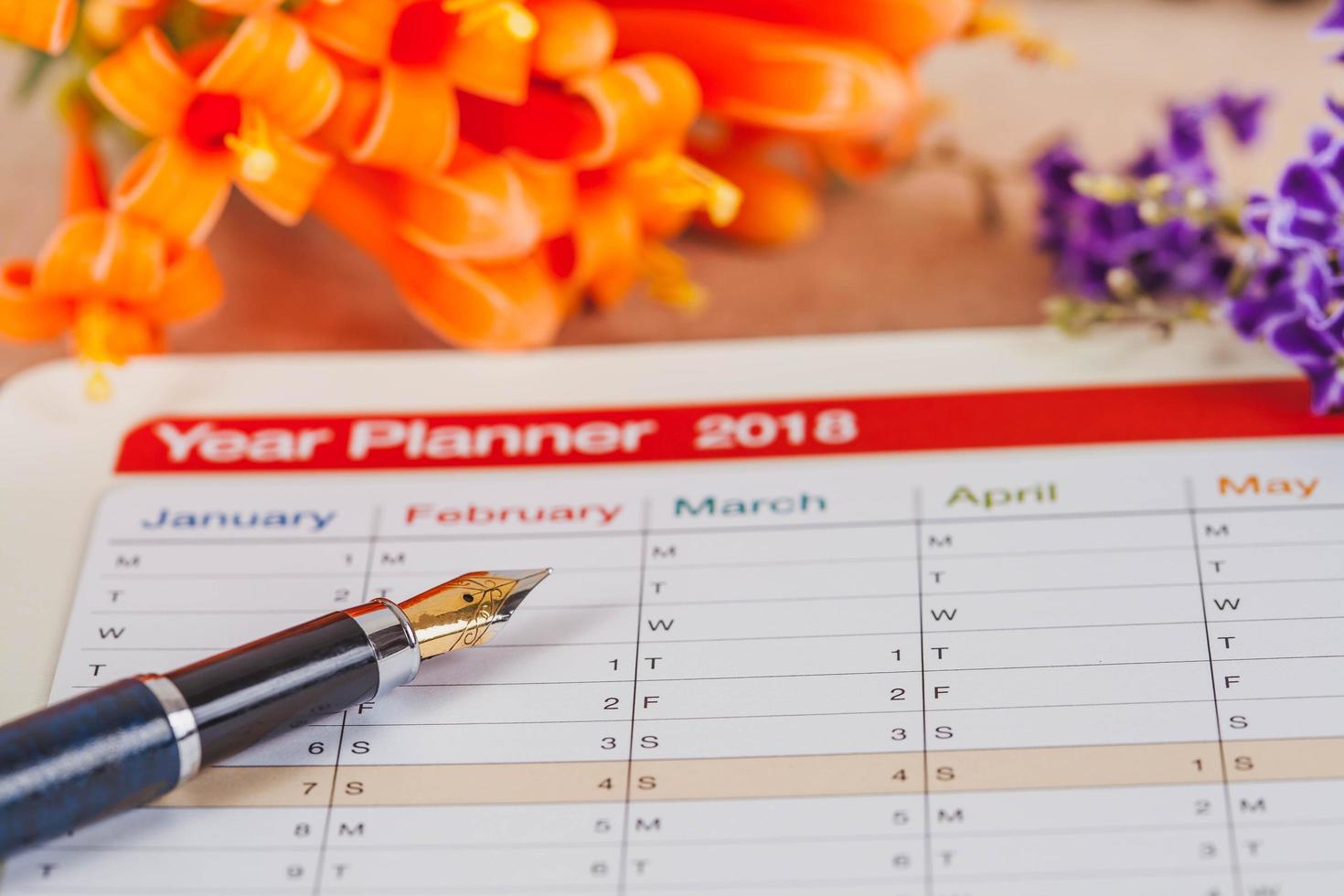 persoonlijk organisator of ontwerper met fontein pen Aan hout tafel. foto