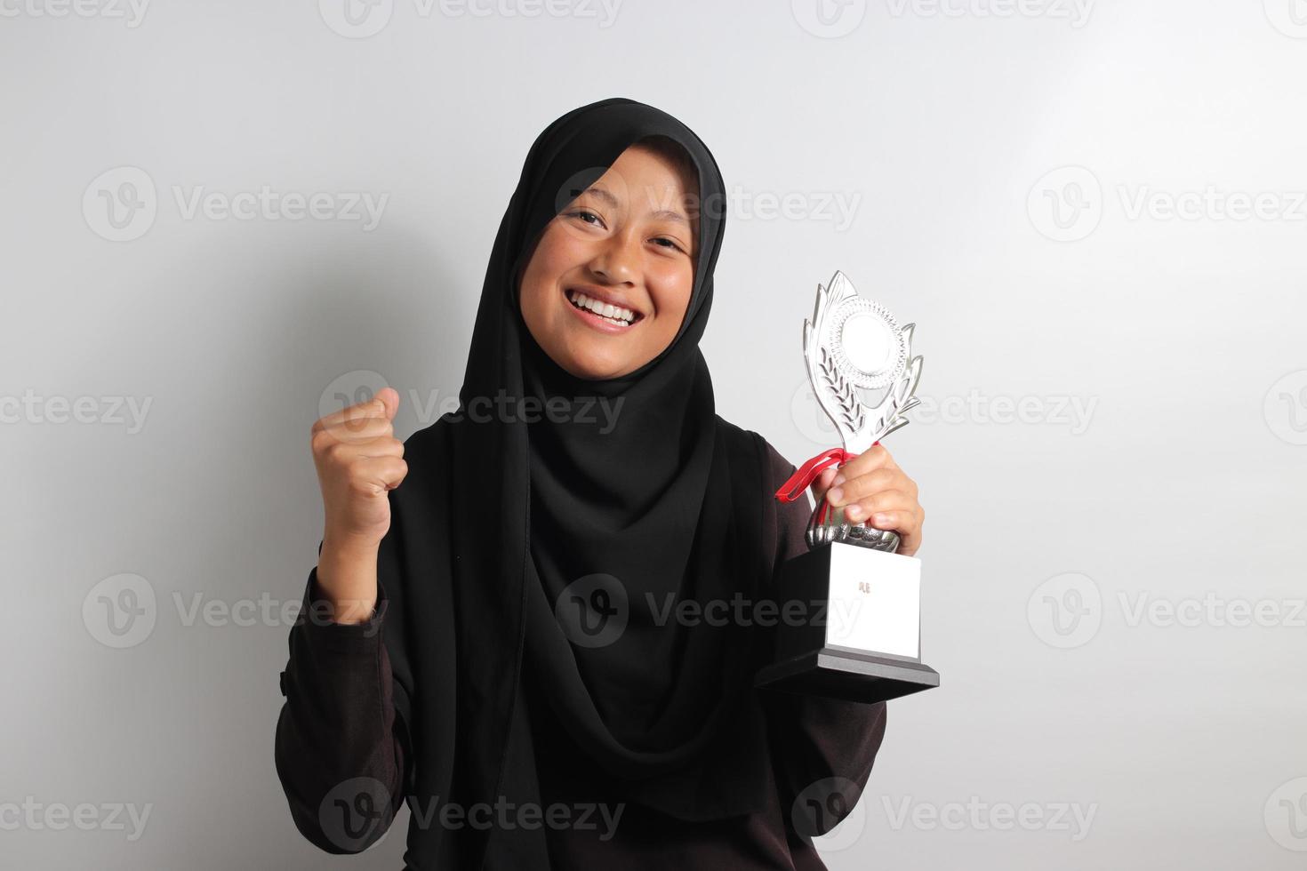 knap jong Aziatisch meisje leerling in hijab verhogen haar trofee geïsoleerd Aan wit achtergrond. foto