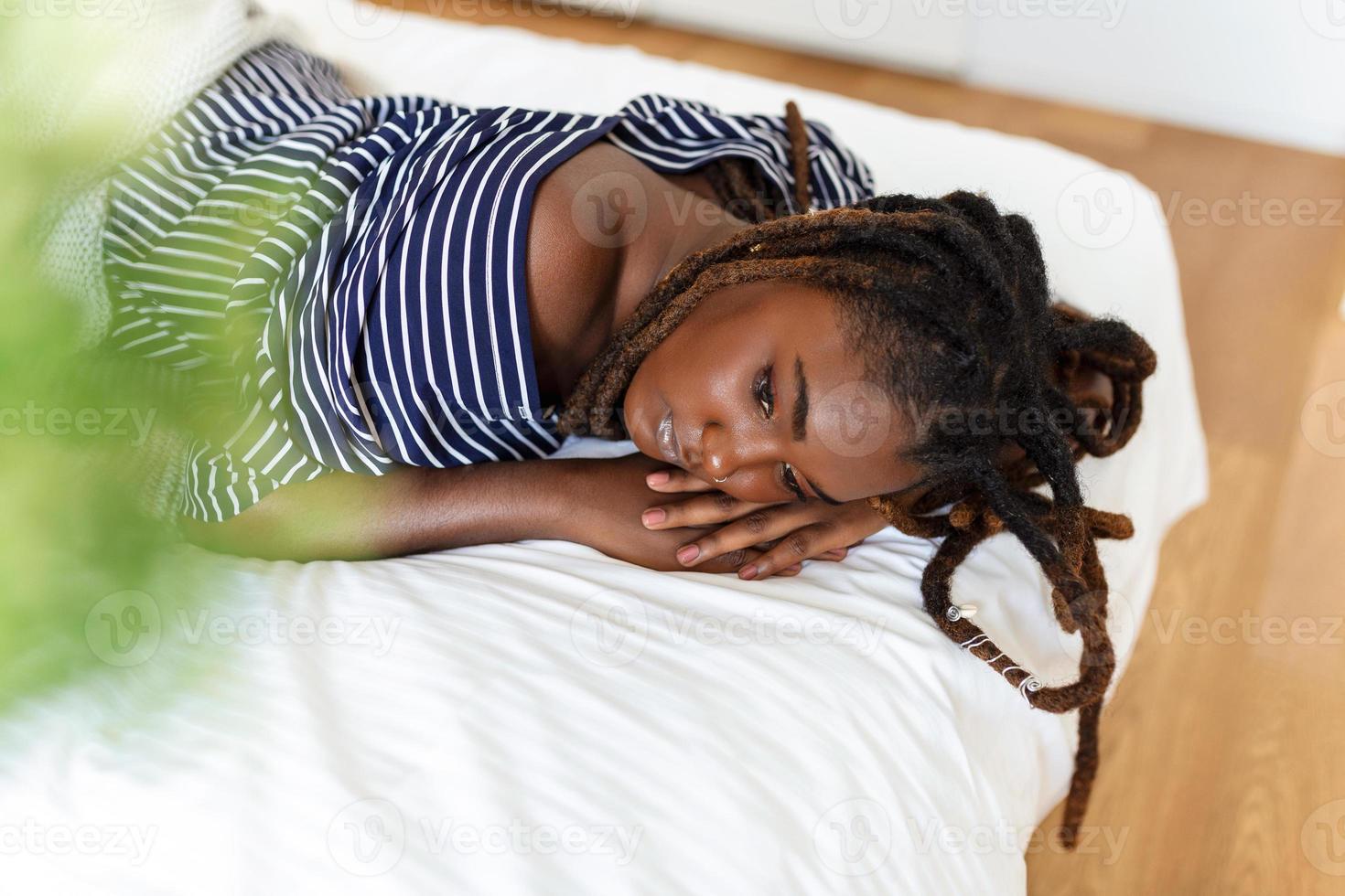 portret van mooi en sensueel Afrikaanse jong vrouw aan het liegen Aan bed. mooi vrouw aan het liegen in bed foto