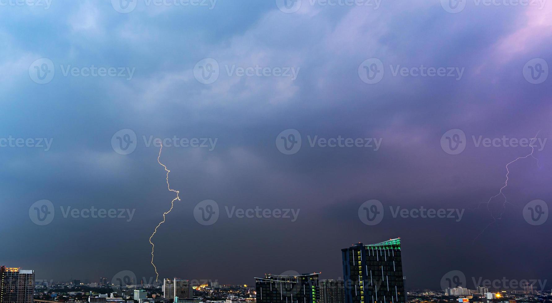 onweer bliksem over de stad bij zonsondergang foto