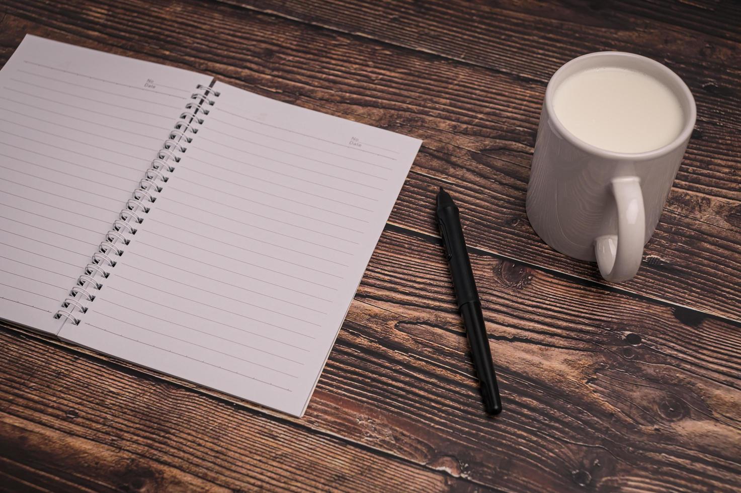 notitieboekje en een glas melk op het bureau foto